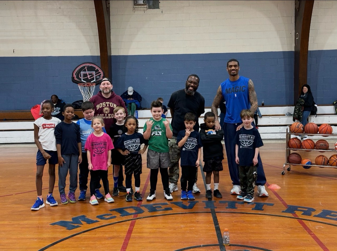 McDevitt Rec Basketball players and coaches pose together at center court in a gym.