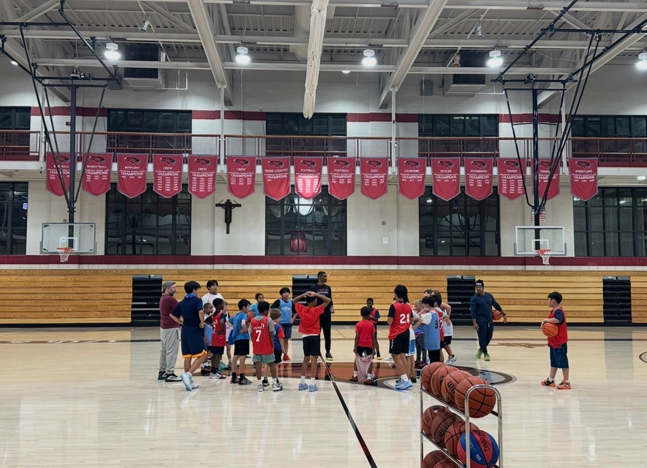 McDevitt Rec Basketball youth players and coaches gather during a basketball session in the gym.